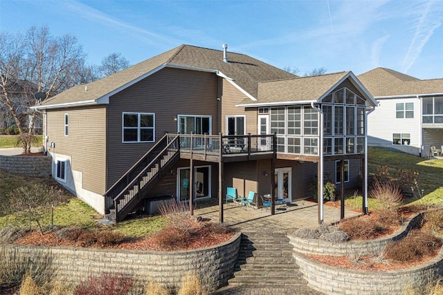 back of property featuring a patio, a sunroom, stairway, a shingled roof, and a wooden deck