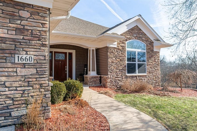 entrance to property with stone siding and a shingled roof