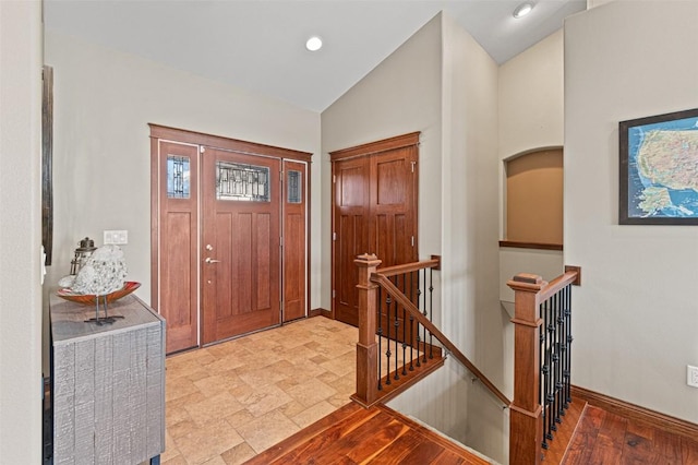 foyer entrance with recessed lighting, stone finish floor, baseboards, and vaulted ceiling