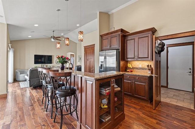 kitchen featuring a kitchen bar, stainless steel fridge with ice dispenser, tasteful backsplash, and dark wood-style flooring