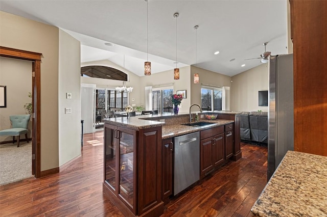 kitchen featuring open floor plan, lofted ceiling, ceiling fan with notable chandelier, appliances with stainless steel finishes, and a sink