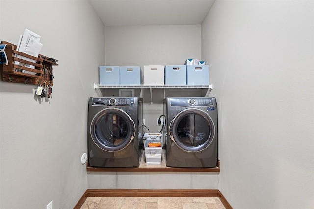 clothes washing area with baseboards, separate washer and dryer, and laundry area