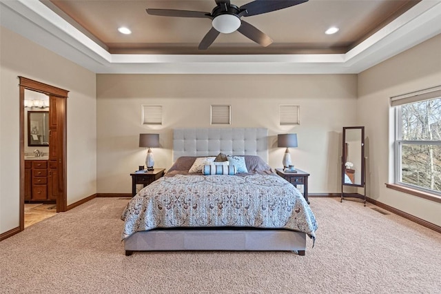 carpeted bedroom featuring recessed lighting, baseboards, a raised ceiling, and connected bathroom