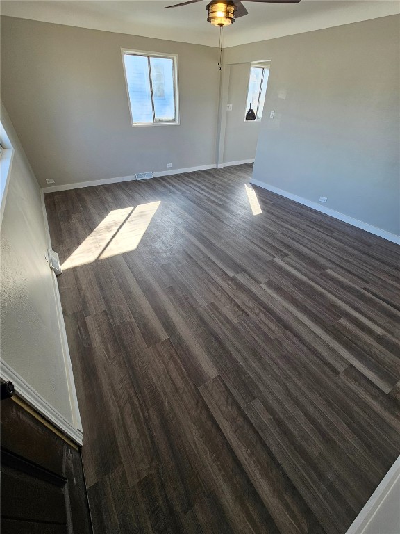 unfurnished room with visible vents, baseboards, dark wood-style floors, and a ceiling fan