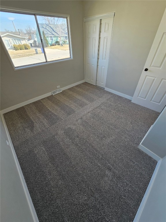 unfurnished bedroom with baseboards, carpet floors, visible vents, and a closet