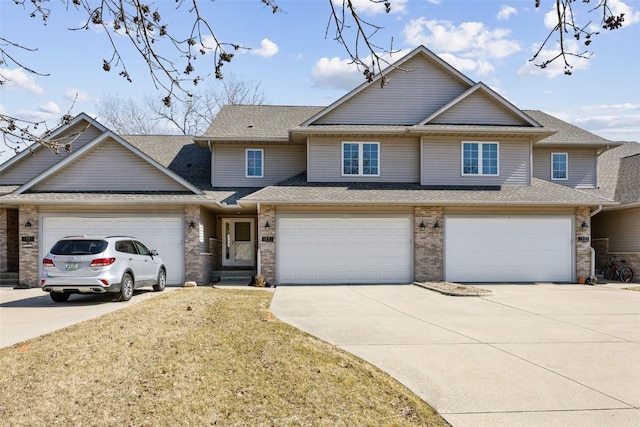 view of front of home featuring concrete driveway, a front yard, brick siding, and roof with shingles