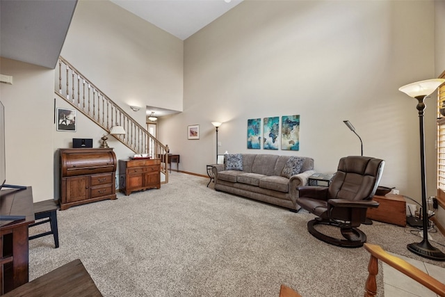 living area with stairway, carpet flooring, baseboards, and a towering ceiling