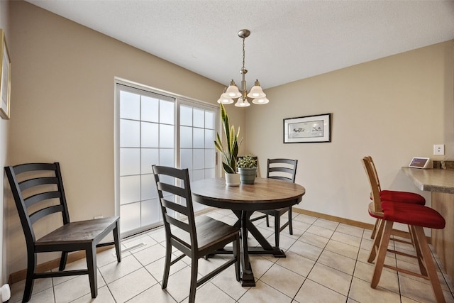 dining area featuring baseboards, a textured ceiling, a chandelier, and light tile patterned flooring