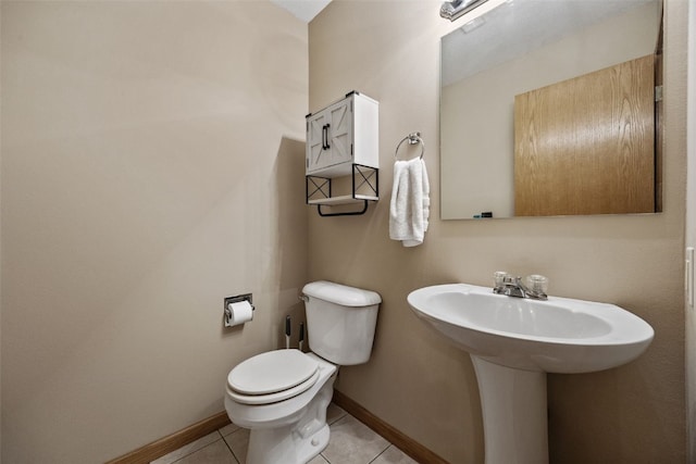 half bath with tile patterned flooring, toilet, and baseboards