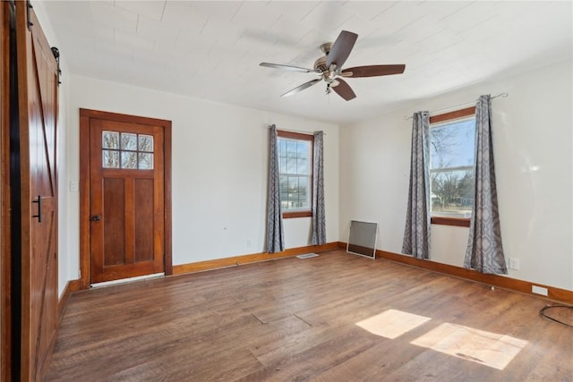 entrance foyer with a barn door, wood finished floors, and baseboards