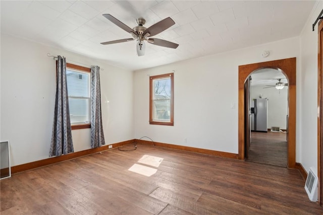 unfurnished room featuring wood finished floors, a ceiling fan, visible vents, and baseboards