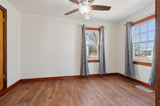 unfurnished room with visible vents, crown molding, baseboards, and wood finished floors