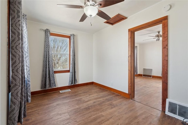 empty room featuring visible vents, baseboards, and wood finished floors