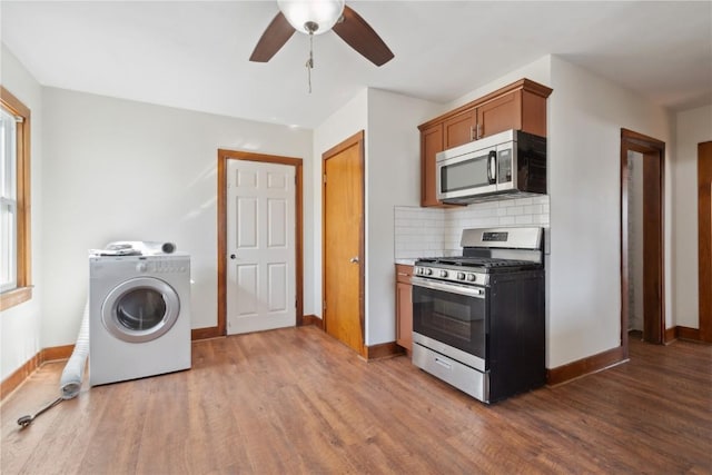 kitchen with wood finished floors, washer / clothes dryer, appliances with stainless steel finishes, and ceiling fan