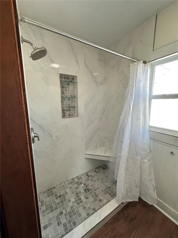 full bathroom featuring a shower stall and wood finished floors