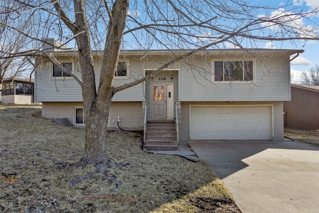 bi-level home featuring a garage, brick siding, driveway, and entry steps