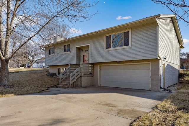 raised ranch featuring a garage, brick siding, and driveway