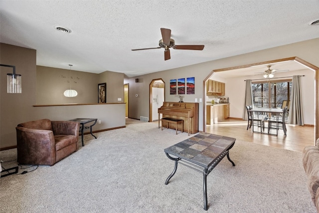 living room with arched walkways, visible vents, and a ceiling fan