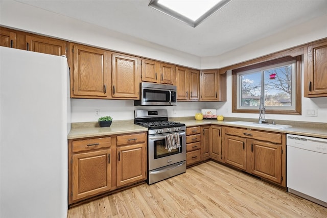 kitchen with brown cabinetry, light wood-style floors, and stainless steel appliances