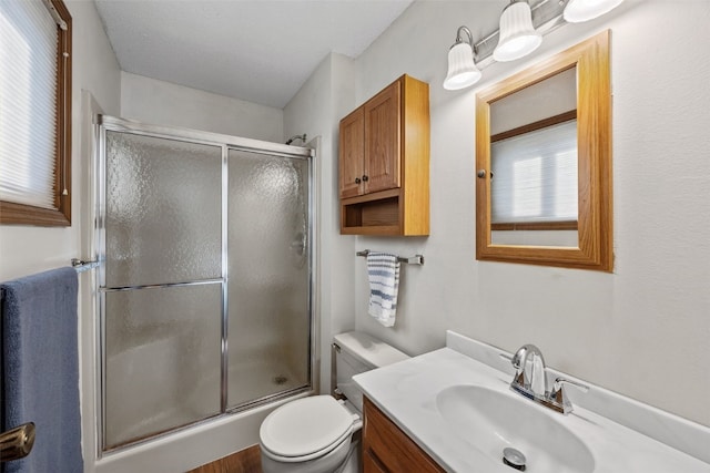 full bath with toilet, vanity, and a shower with shower door