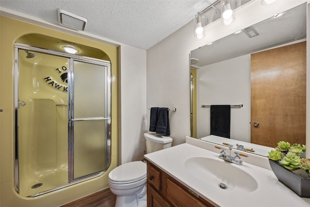 full bath featuring vanity, a shower stall, toilet, and a textured ceiling