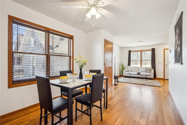 dining area featuring light wood finished floors, baseboards, and a ceiling fan