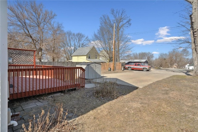 view of yard with an outbuilding, a shed, a deck, and fence