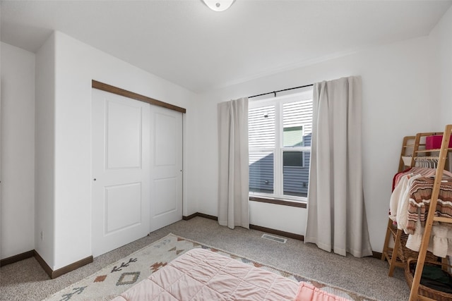 carpeted bedroom featuring a closet, visible vents, and baseboards