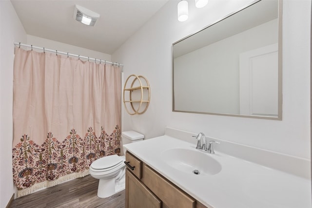 bathroom featuring visible vents, toilet, a shower with shower curtain, wood finished floors, and vanity