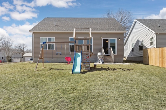 back of house featuring a playground, a lawn, entry steps, and fence