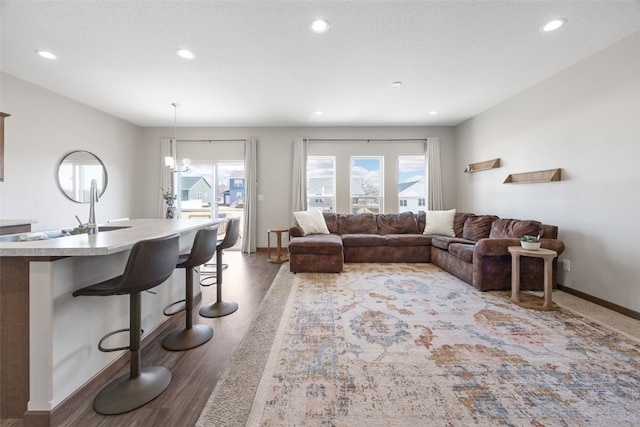 living room with recessed lighting, baseboards, an inviting chandelier, and wood finished floors