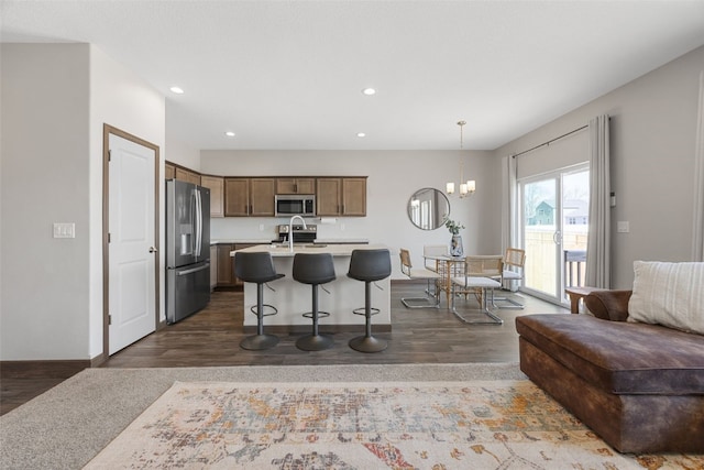 kitchen with open floor plan, a breakfast bar, light countertops, an inviting chandelier, and stainless steel appliances