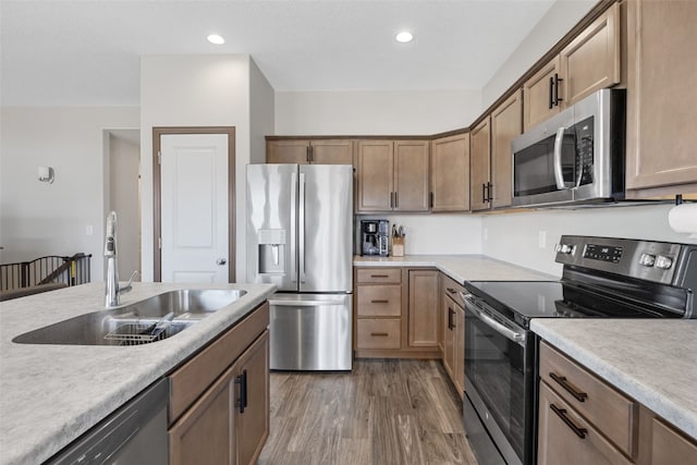 kitchen with wood finished floors, recessed lighting, a sink, light countertops, and appliances with stainless steel finishes