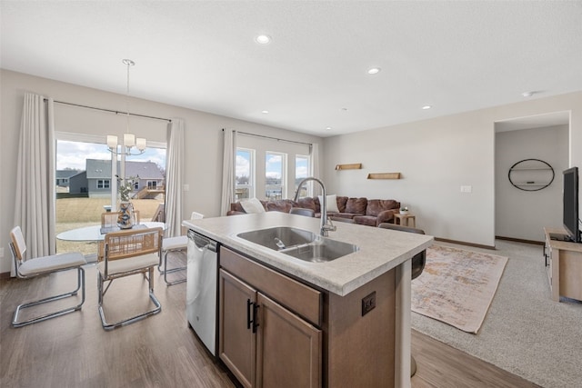 kitchen featuring a center island with sink, a sink, open floor plan, light countertops, and dishwasher