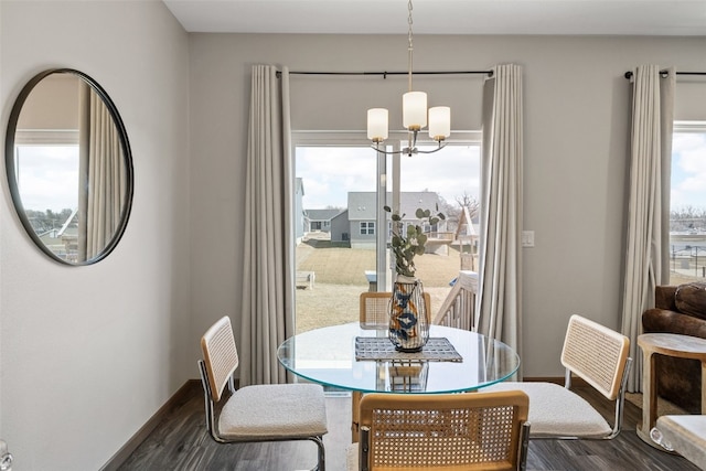 dining area featuring baseboards, a healthy amount of sunlight, dark wood finished floors, and an inviting chandelier