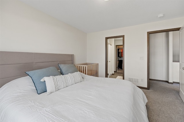 bedroom with visible vents, baseboards, a walk in closet, and carpet