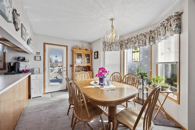 dining area with a notable chandelier, light colored carpet, baseboards, and a textured ceiling