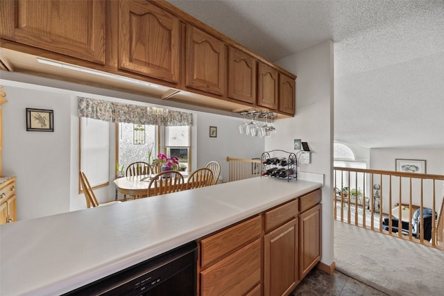 kitchen featuring brown cabinets, a textured ceiling, black dishwasher, light countertops, and dark colored carpet