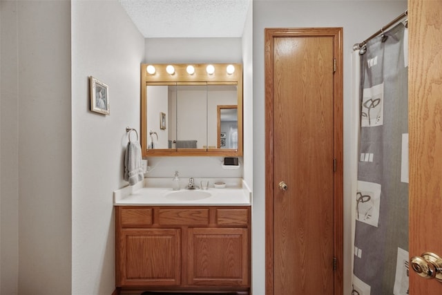 full bath featuring vanity, curtained shower, and a textured ceiling