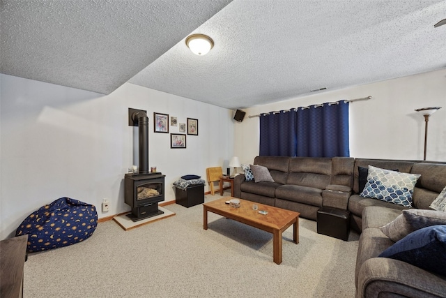 living room featuring carpet, baseboards, visible vents, a wood stove, and a textured ceiling