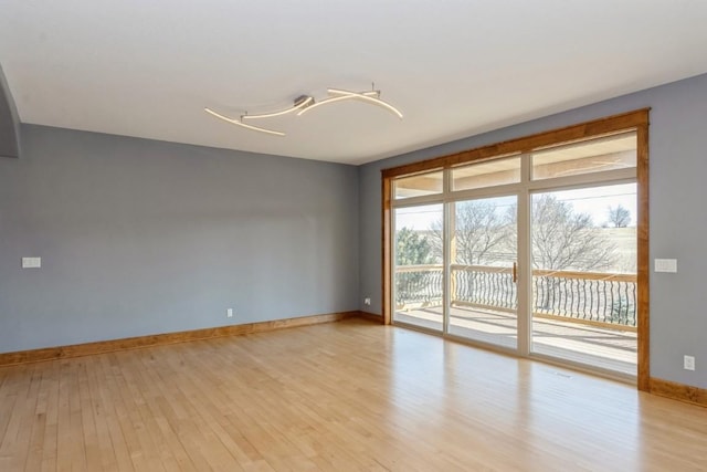 spare room featuring light wood-type flooring and baseboards