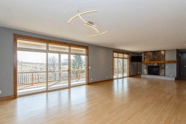 unfurnished living room with light wood-style flooring, a fireplace, and baseboards