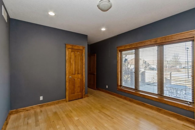 unfurnished room featuring baseboards and light wood-type flooring