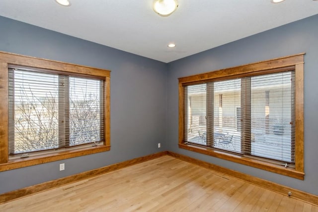 unfurnished room with recessed lighting, a healthy amount of sunlight, baseboards, and wood finished floors