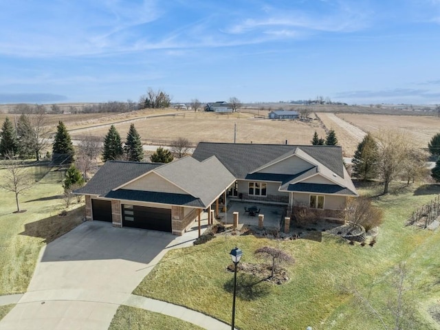 view of front of home with a front yard, a rural view, concrete driveway, and an attached garage