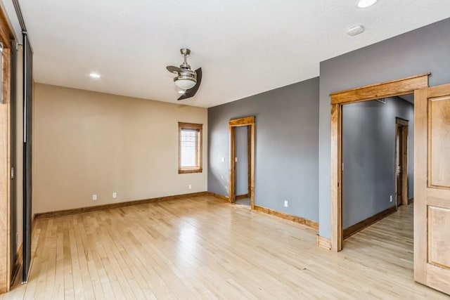 unfurnished room with a ceiling fan, light wood-type flooring, and baseboards