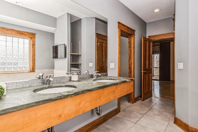 full bathroom featuring tile patterned floors, double vanity, baseboards, and a sink