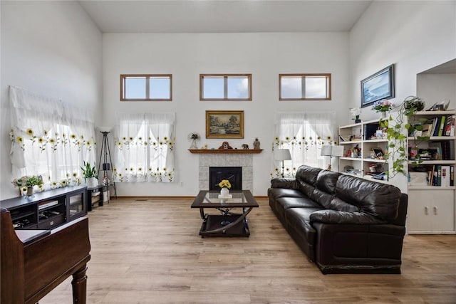 living area with baseboards, a high ceiling, wood finished floors, and a fireplace