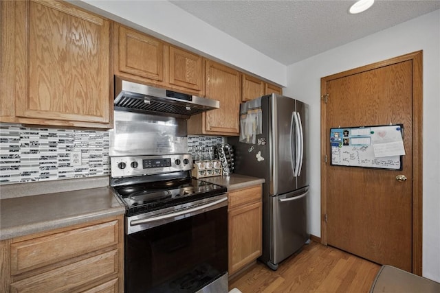 kitchen with light wood-type flooring, backsplash, a textured ceiling, range hood, and appliances with stainless steel finishes