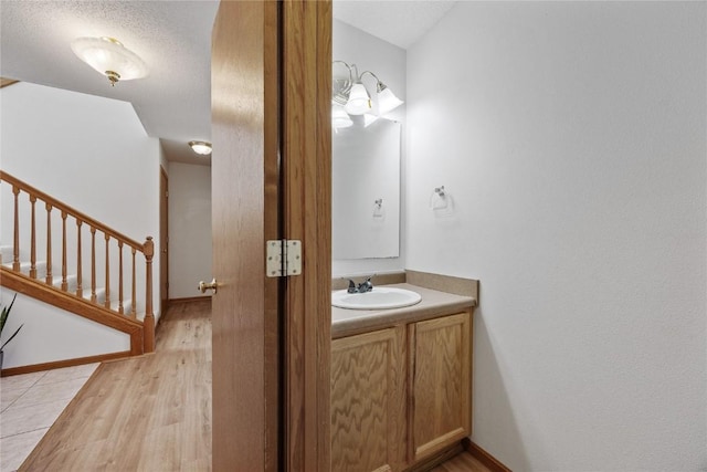 bathroom with a textured ceiling, vanity, and wood finished floors